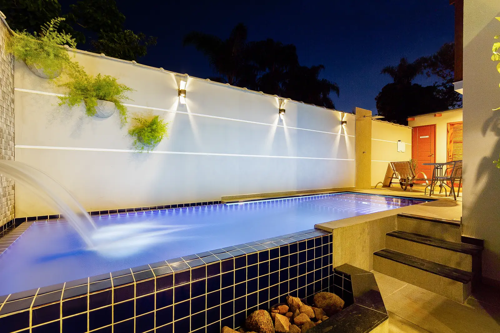 Piscina com cascata iluminada à noite